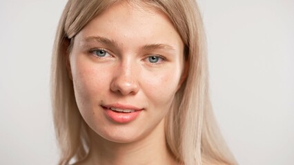 Young blonde woman posing at camera looking and smiling naturally, positive expression, isolated on white studio background. Beauty skin care concept