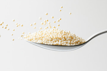 A spoonful of white rice is shown with a lot of rice grains scattered around it