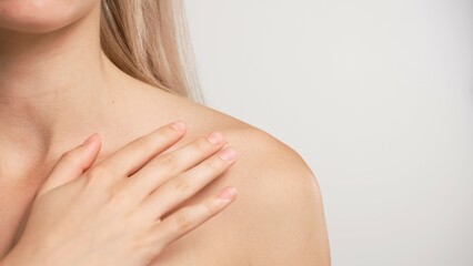 Young blonde woman posing at camera, touching shoulders looking naturally, isolated on white studio background close up shot. Beauty skin care concept