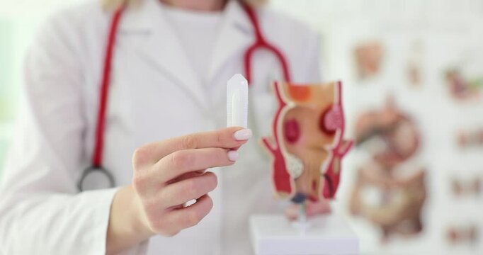 Proctologist doctor holds rectal suppository and artificial model of human rectum. Vascular structures in lower rectum and concept of acute pain treatment