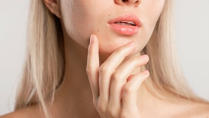 Fototapeta premium Young blonde woman posing at camera touching face line with hand, isolated on white studio background close up shot. Beauty skin care concept