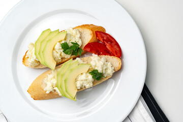 Fresh avocado and cheese spread on toasted bread garnished with cilantro and tomato