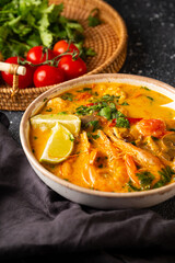 Tom yum soup with shrimp, sea food and lime on dark background vertical photo