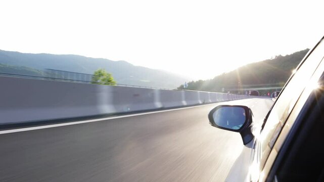 The car going on a bumpy highway. The road is between the mountains and continues in the tunnel.