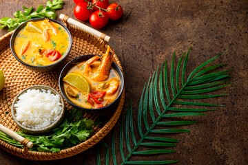 Two bowl of tom yum soup with shrimp, sea food and lime on dark brown background