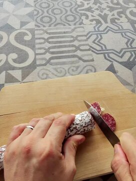 saucisson coup&eacute; en rondelles sur une planche &agrave; d&eacute;couper