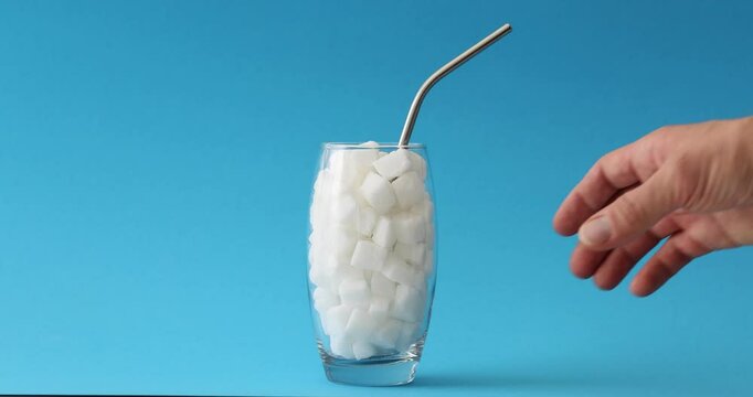 Glass full of sugar cubes and unhealthy eating concept. Uncontrolled sugar intake