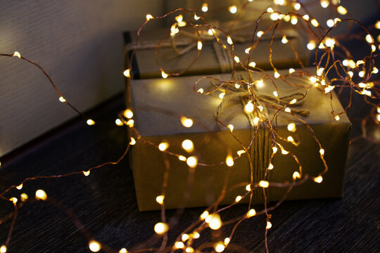 Golden Christmas gift wrapped and surrounded by twinkling lights