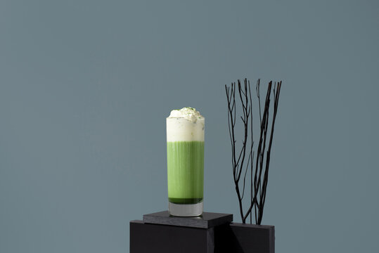 Matcha tea latte with whipped cream on modern background