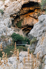 Natural cave entrance with rugged rocky formations and green plants growing around the Cueva del Gato in Ronda, Andalusia, Spain