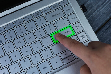 A person is pressing a green button on a laptop keyboard