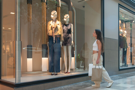 Young woman shopping, pausing to admire store window