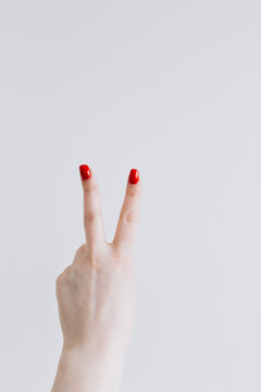 Hand Showing Reverse V-Sign with Red Nails on White Background
