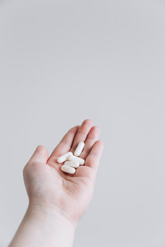 Hand holding white pills isolated on a clean background