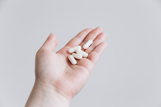 Hand holding white pills on isolated background