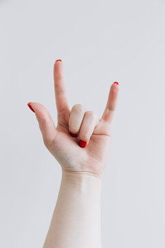 Female hand gesturing rock sign against white background