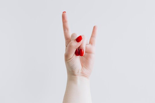 Hand Making the Rock and Roll Sign with Red Nails on White Background - Powered by Adobe