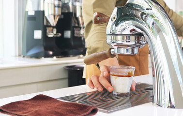 Single head espresso machine with coffee measuring cup in barista hand.