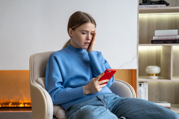 Upset woman received bad stressed news on phone, following ex-boyfriend on social media, sits with awful thoughts at home. Worried unhappy female using smartphone being cheated, hacked feels shock. © DimaBerlin