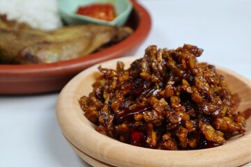 Stir-fried Tempe is a typical Indonesian dish with spices, garlic, shallots, chilies and soy sauce. served on a wooden plate