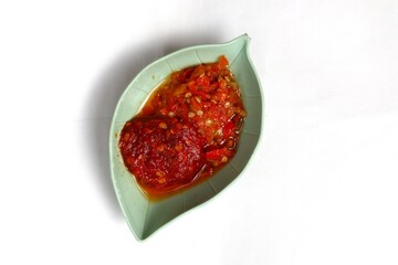 Traditional Indonesian chili sauce namely crushed chilies with shrimp paste, garlic, shallots and spices served in a bowl isolated on a white background