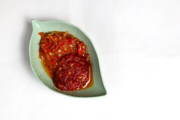 Traditional Indonesian chili sauce namely crushed chilies with shrimp paste, garlic, shallots and spices served in a bowl isolated on a white background
