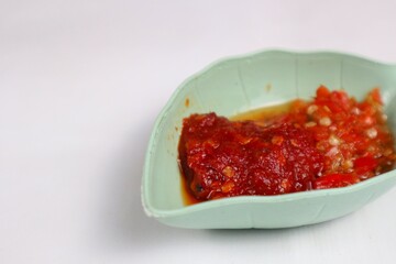 Traditional Indonesian chili sauce namely crushed chilies with shrimp paste, garlic, shallots and spices served in a bowl isolated on a white background