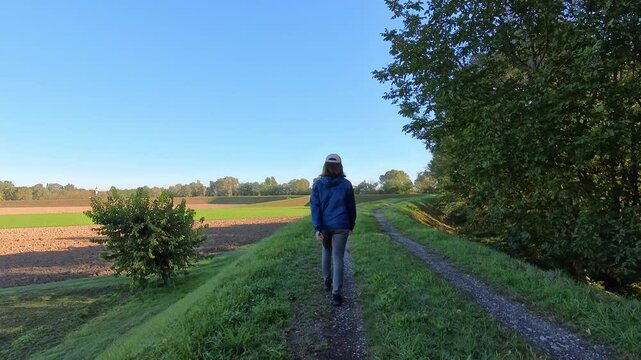 Woman Strolls Along a Forest Trail on a Sunny Day