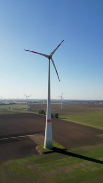 Windturbinen in herbstlicher Landschaft im Gegenlicht. Aufnahmen eines Windparks zur Erzeugung erneuerbarer Energie. Aerial, Hochformat