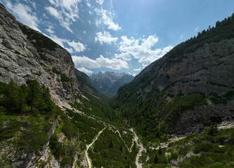 Lush green valley with rocky mountains and a partly cloudy sky
