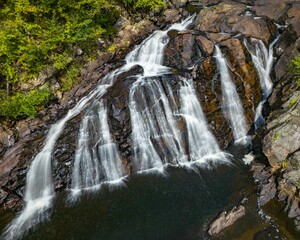 Obraz premium Waterfall cascading over rocky terrain in a forest