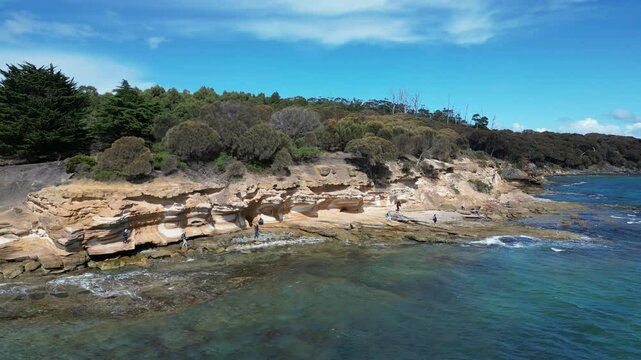 Aerial footage of a group of people visiting the Painted Cliffs on Maria Island, Tasmania, Australia
