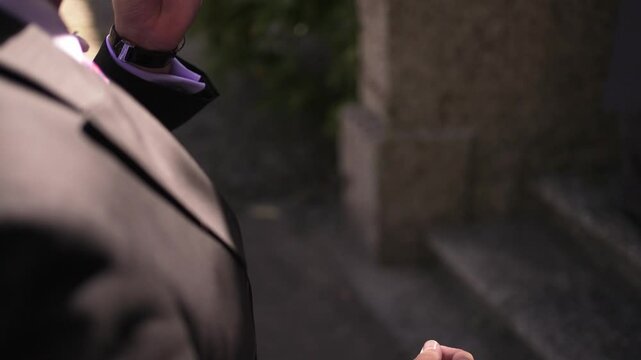Person in a suit holding a slice of pizza outdoors