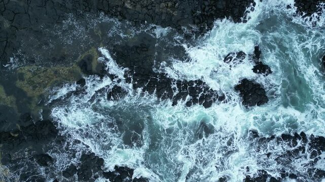 Aerial footage of foam waves splashing rocky hills in Philip Island, Australia
