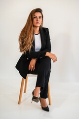 Confident young woman in a business suit sitting on a chair.