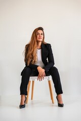 Confident young woman in business attire sitting on a chair.
