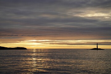 Obraz premium Scenic view of a lighthouse on a small island during sunset