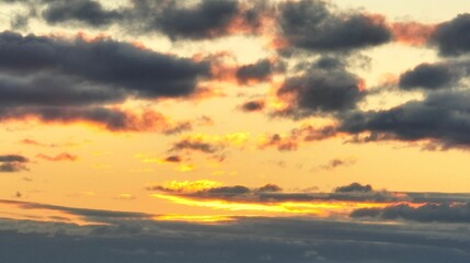 Serene sunset sky with dark clouds and vibrant hues.