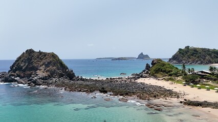 Obraz premium Stunning beach landscape with rocky hills and clear blue waters.