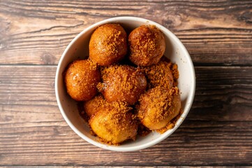 Honey-covered doughnuts topped with brown sugar in a bowl.