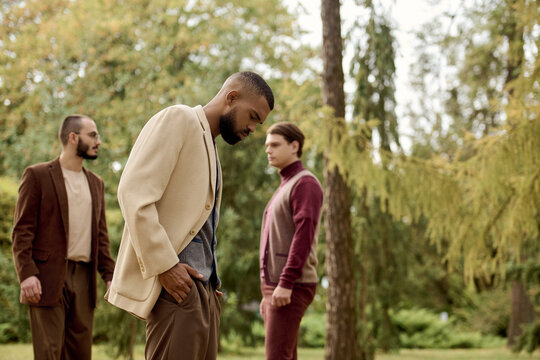 Three men exude charm and elegance while posing in a stunning autumn field filled with colorful foliage.