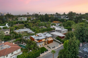 Obraz premium Aerial view of a modern house in a lush neighborhood at sunset.