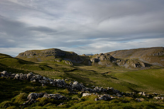Scenic view of rolling hills and rocky formations under a cloudy sky in Skipton town, England, UK