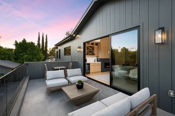 Modern outdoor patio with seating and glass railing at sunset.