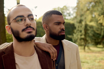 Handsome gentlemen in trendy autumn outfits enjoy a serene moment in a vibrant outdoor setting.