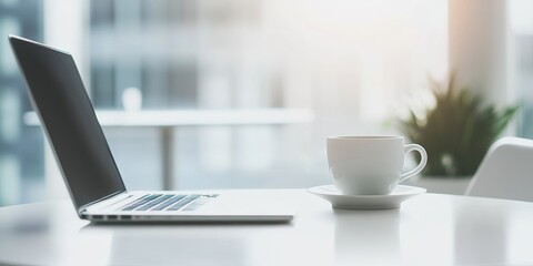 Blurred modern home office interior featuring a laptop and coffee cup on a white table, designed as a versatile banner background with ample copy space.