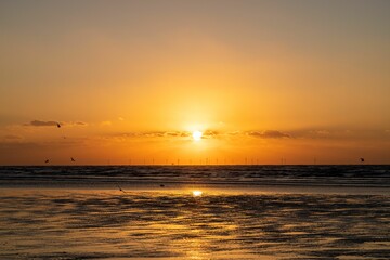 Obraz premium a sunset with the sun setting behind a cloud filled sky