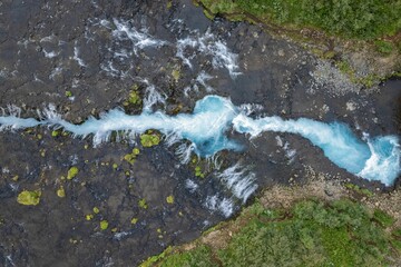 Aerial view of a clear blue river flowing through rocky terrain.