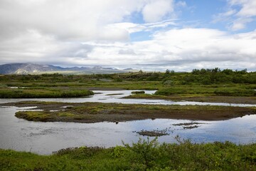Scenic view of a lush green landscape with a meandering river under a partly cloudy sky.