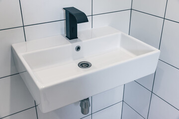 Black bathroom faucet and white square sink..Modern minimalist bathroom design.
